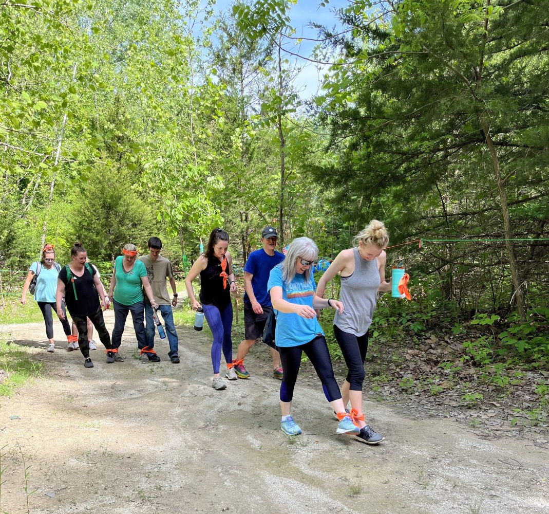 A team Building group on a dirt road in the woods participating in the Three Legged hike.