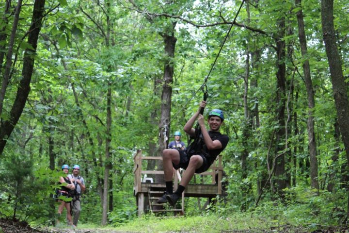 a man sitting on a bench next to a forest