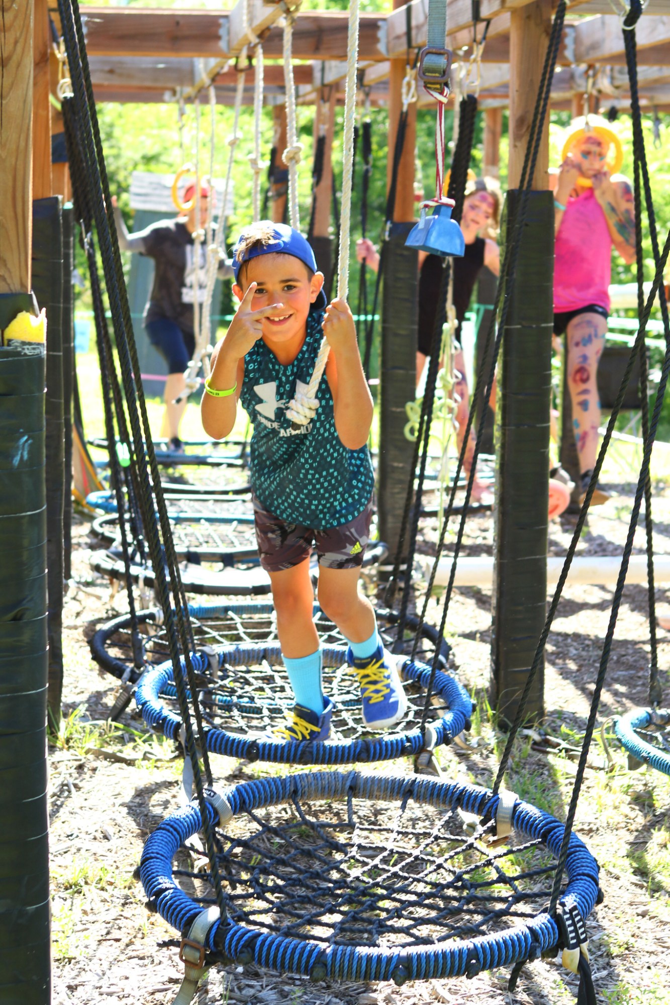 Child navigating ropes on outdoor obstacle course.